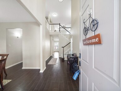 Step inside to a light-filled entryway with elegant wood-look tile and soft neutral tones that flow throughout the main living spaces.