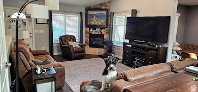 Living room with healthy amount of natural light, vaulted ceiling, wood finished floors, and a stone fireplace