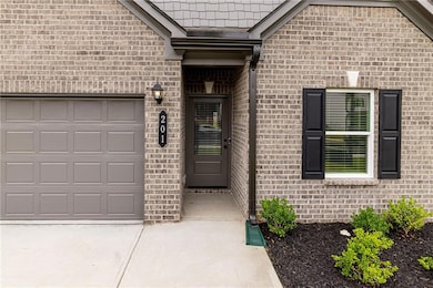Doorway to property with a garage, brick siding, and concrete driveway