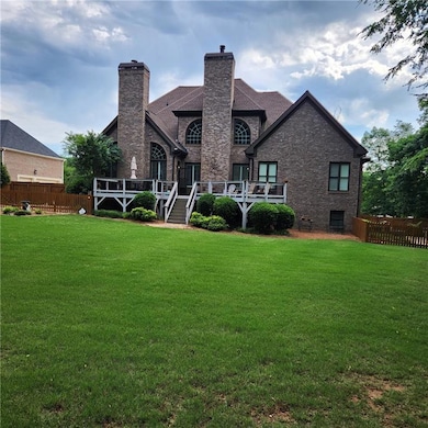 Back of house featuring a chimney, a deck, and brick siding