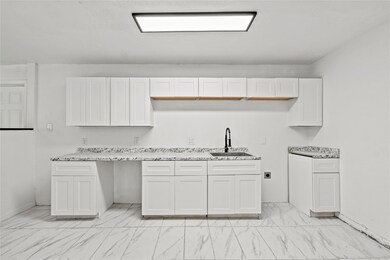 Kitchen with white cabinets, light stone counterto