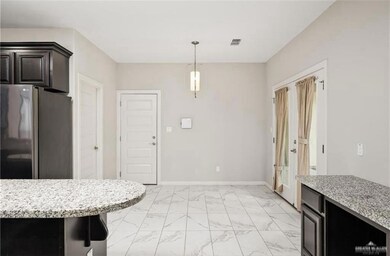 Kitchen featuring decorative light fixtures, stainless steel refrigerator, light stone counters, and light tile floors
