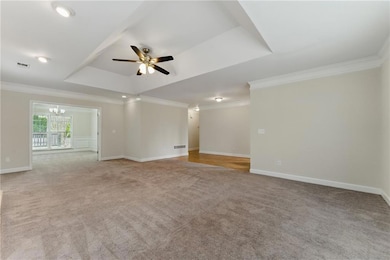 Empty room featuring light carpet, ceiling fan wit
