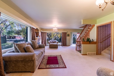 Carpeted living area featuring a chandelier and stairs