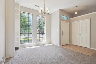 Entryway with a textured ceiling, a chandelier, and light tile patterned flooring
