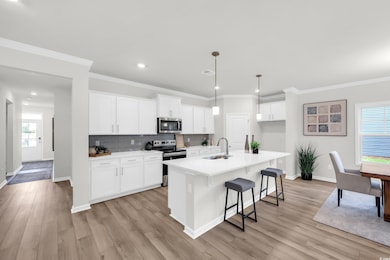 Kitchen with stainless steel appliances, a kitchen breakfast bar, white cabinetry, crown molding, and decorative backsplash