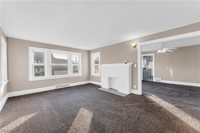 Unfurnished living room featuring dark carpet, ceiling fan, and a fireplace