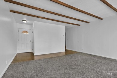 Carpeted spare room featuring beam ceiling and baseboards