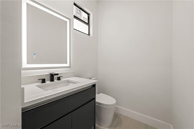 Half bathroom featuring toilet, vanity, and basebo