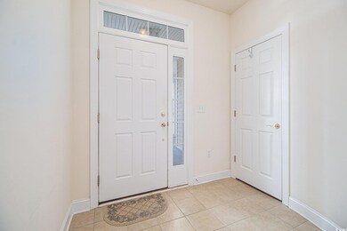 Foyer with light tile patterned floors and baseboards