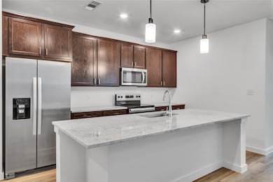 Kitchen featuring light wood-style flooring, dark brown cabinetry, a sink, visible vents, and appliances with stainless steel finishes