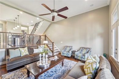 Living room with wood finished floors, stairway, a ceiling fan, ornamental molding, and recessed lighting