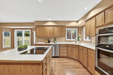 Bright, functional kitchen offering abundant counter space, double ovens, a center island with cooktop, and picturesque views of the backyard through multiple windows.