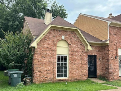 Exterior space with brick siding, a chimney, a yard, and a shingled roof
