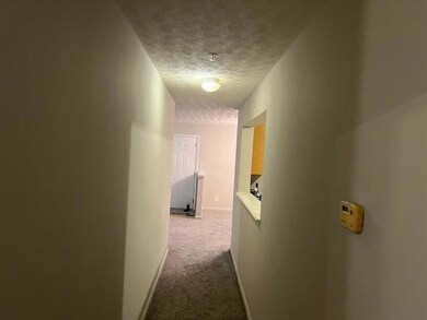 Corridor with a textured ceiling and dark colored carpet