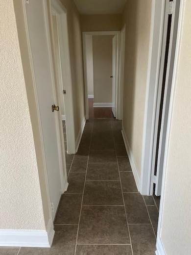 Corridor with dark tile patterned floors and baseboards