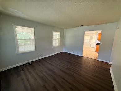 Spare room with a textured ceiling and dark wood-type flooring