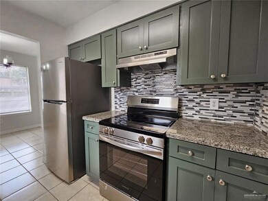 Kitchen with under cabinet range hood, appliances with stainless steel finishes, light tile patterned floors, tasteful backsplash, and green cabinets