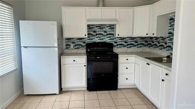 Kitchen featuring freestanding refrigerator, black electric range oven, a sink, light countertops, and backsplash