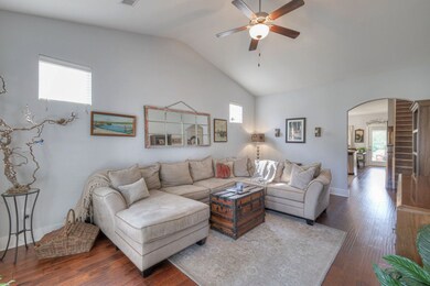 This spacious living room offers an abundance of natural light, a vaulted ceiling, and hardwood floors through the main level.