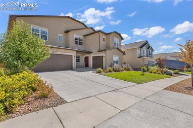 Traditional-style home featuring an attached garage, driveway, stucco siding, and a front lawn