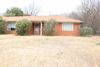 Ranch-style home with brick siding, a chimney, and