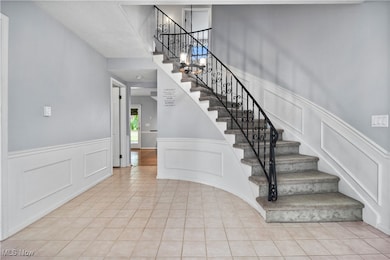 Staircase featuring wainscoting, a decorative wall, and tile patterned flooring