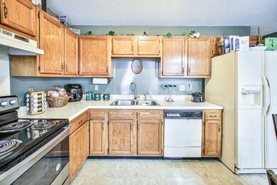 Kitchen featuring a textured ceiling, sink, and wh