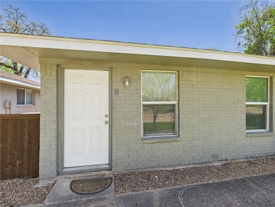 Doorway to property with brick siding and fence