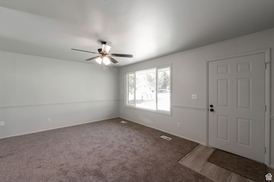 Carpeted entrance foyer with baseboards and ceiling fan