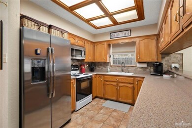 Kitchen featuring sink, backsplash, light tile flooring, and stainless steel appliances