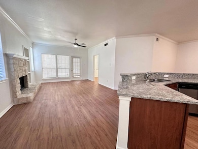 Kitchen featuring crown molding, light stone counters, dark wood-style floors, stainless steel dishwasher, and open floor plan