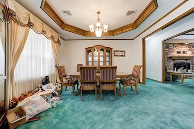 Carpeted dining area with a raised ceiling, a chan