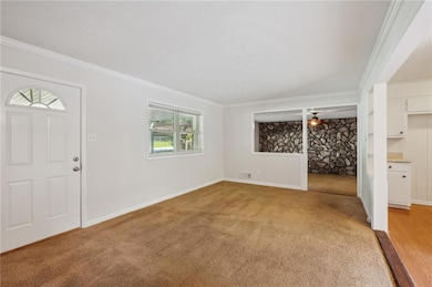 Entryway with plenty of natural light, ornamental molding, light carpet, baseboards, and a ceiling fan