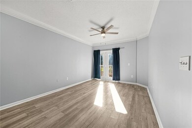 Empty room with a textured ceiling, crown molding, light wood finished floors, french doors, and a ceiling fan