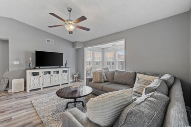 Living room with ceiling fan, vaulted ceiling, wood finished floors, a textured ceiling, and baseboards