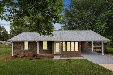Ranch-style home with driveway, a carport, brick siding, metal roof, and crawl space