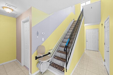 Staircase with iron railing and chairlift. This photographer was facing the closed front door straight ahead. Door to the left of the chairlift goes into the 1/2 bath; door on the right side of photo leads into the garage.