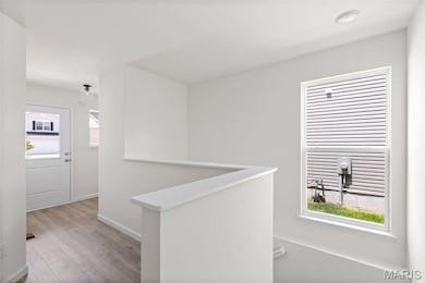 Hallway featuring an upstairs landing and light wood-style floors