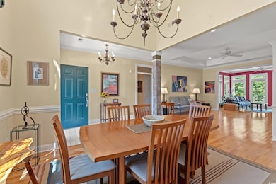 Dining room featuring light wood-type flooring, a ceiling fan, ornate columns, ornamental molding, and a chandelier