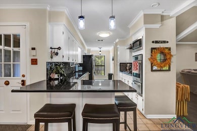 Kitchen with appliances with stainless steel finishes, a warming drawer, crown molding, tasteful backsplash, and a peninsula