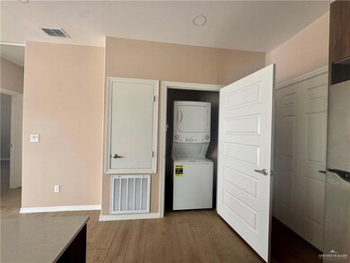 Washroom featuring laundry area, stacked washing maching and dryer, visible vents, and wood finished floors
