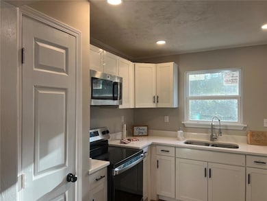 Kitchen featuring white cabinetry, appliances with stainless steel finishes, sink, and a textured ceiling