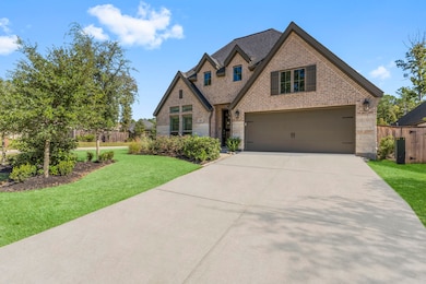 This photo showcases a charming one-story brick & stone home with a gabled roof & a two-car garage. (grass has been enhanced)