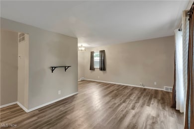 Empty room with wood finished floors and a chandelier