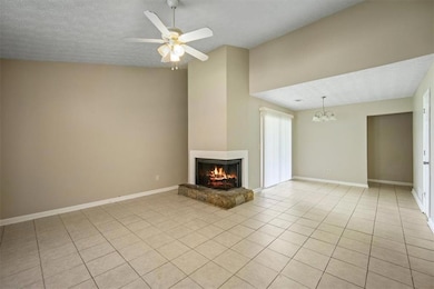 Unfurnished living room with a multi sided fireplace, lofted ceiling, a chandelier, light tile patterned floors, and a ceiling fan