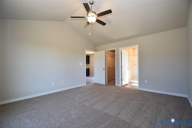 Unfurnished bedroom featuring vaulted ceiling, carpet floors, a spacious closet, and ceiling fan