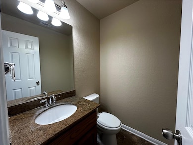 Half bath featuring vanity and a textured wall
