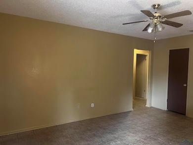 Unfurnished room with a ceiling fan, a textured ce