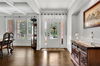 Foyer with beamed ceiling, plenty of natural light, ornamental molding, a decorative wall, and dark wood finished floors